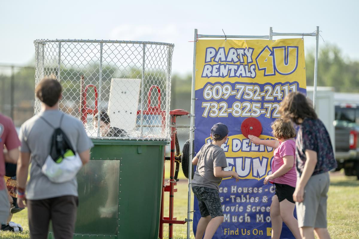 Dunking booth with people participating in the dunking process vendor sign of Party Rentals For You sign