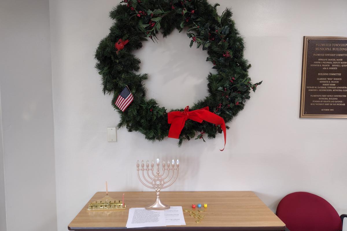 Wreath on wall and menorah with paper list of Hanukkah blessings to be read