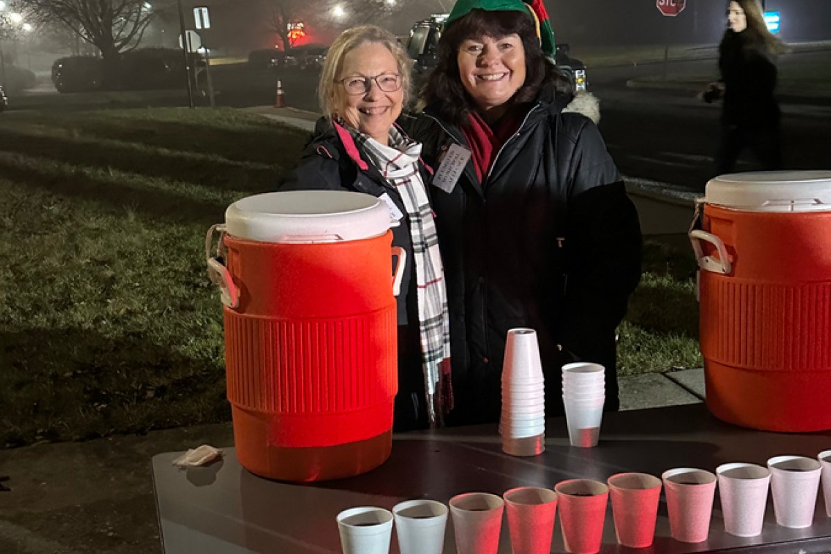 Two ladies manning a hot cocoa table for people who attended the tree lighting event