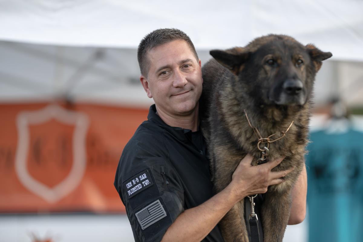 Seach and rescue handler with K9 partner perched on his shoulder