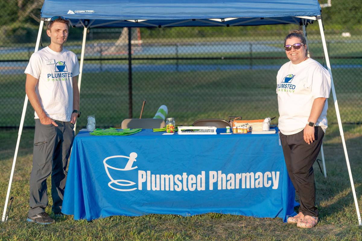 Plumsted Pharmacy tent with two staff members standing on either side
