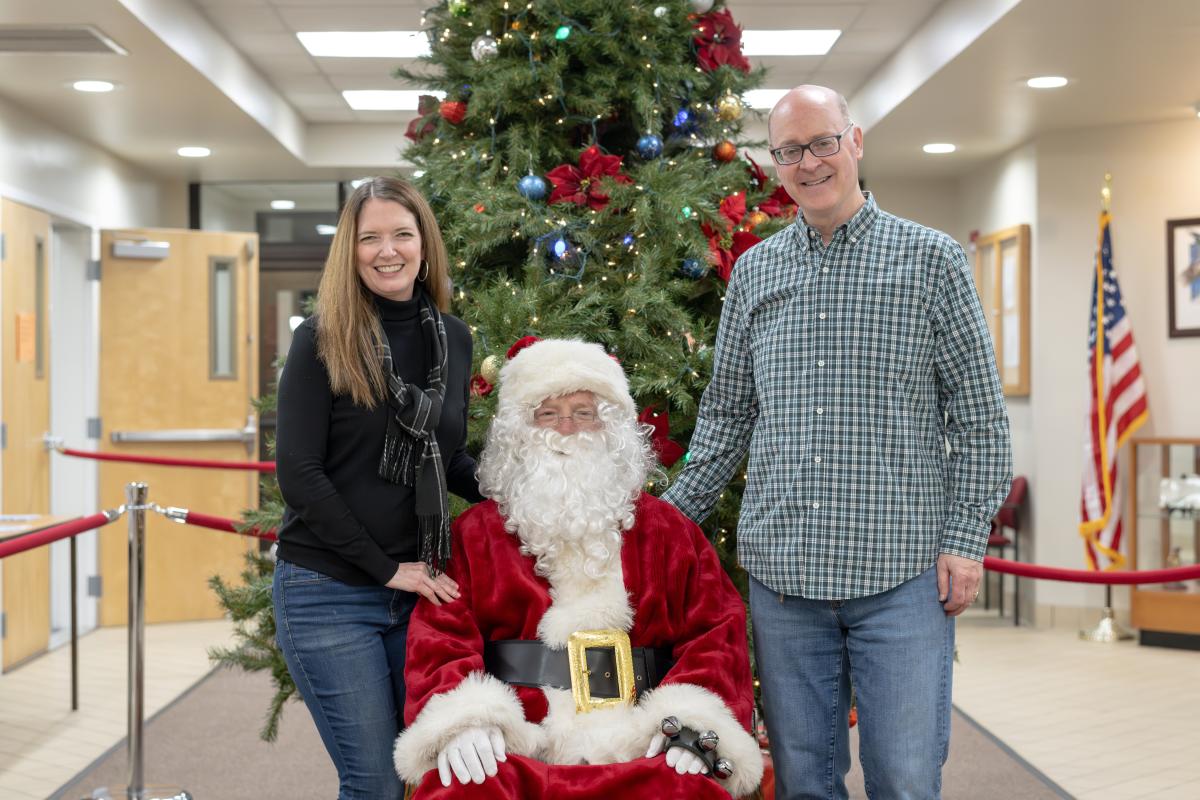 Mayor Robert Bowen and his wife standing on either side of a sitting Santa in front of Christmas Tree