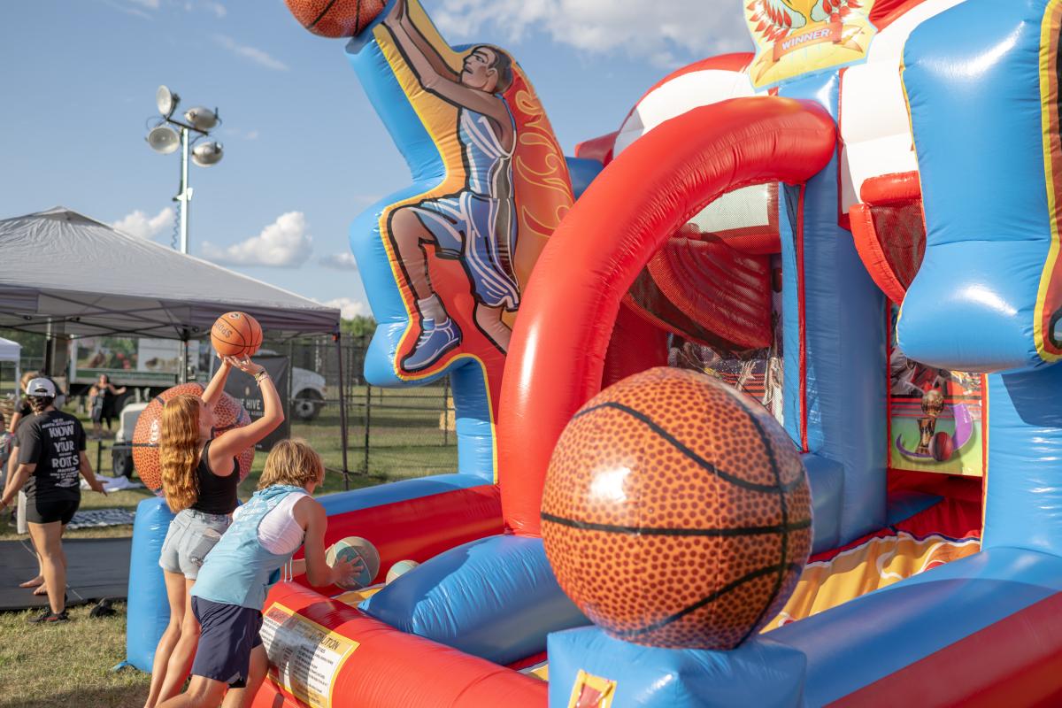 Young girl and young boy shooting hoops at blowup basketball attraction